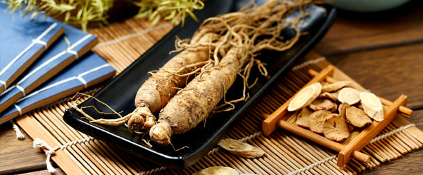 Ganze Wurzeln und geschnittener Ginseng liegen auf einem schönen Holztisch.